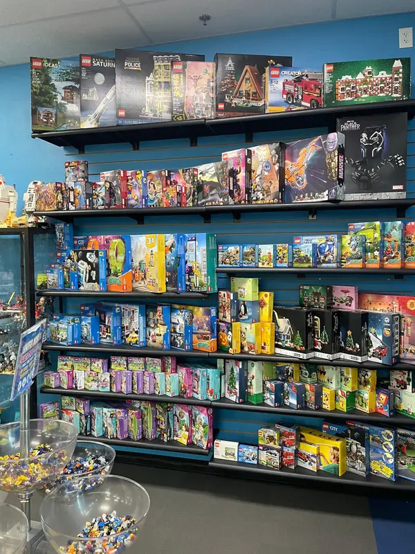 Rows of boxed LEGO® sets on dark shelves against a blue store wall.