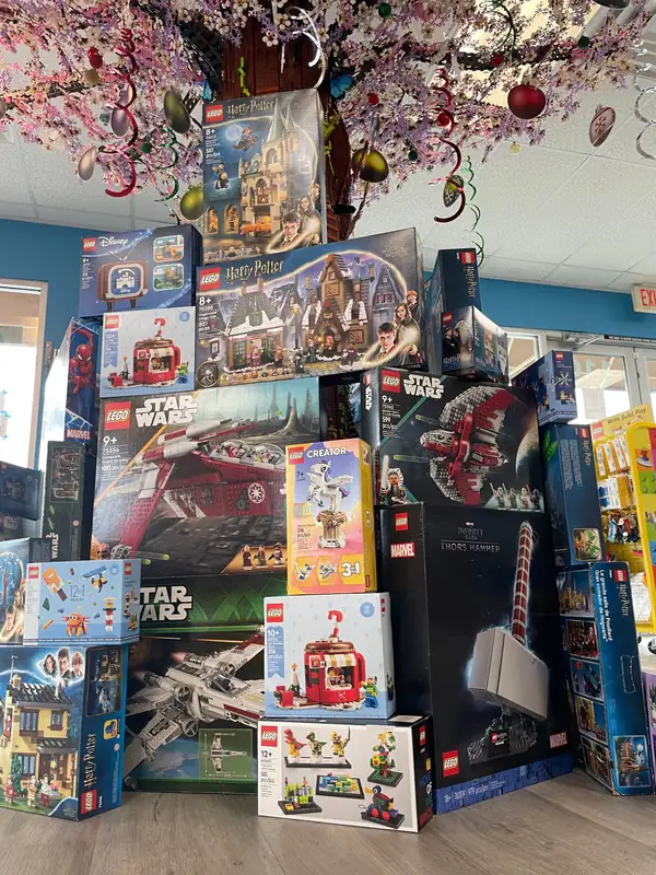 A tall stack of boxed LEGO® sets beside the decorated store tree.