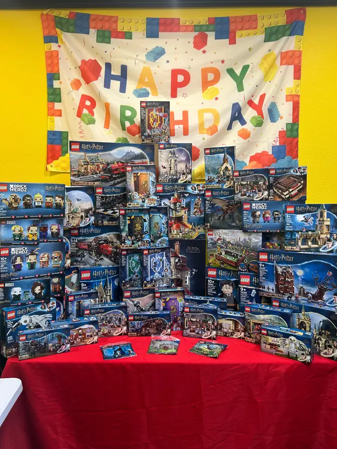 Boxed LEGO® Star Wars sets arranged on a red table below a birthday banner.