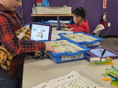 Children building with LEGO® parts and a tablet at an activity table.