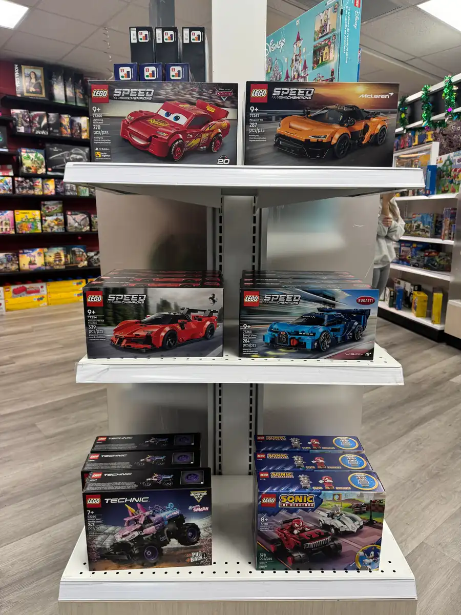 Boxed LEGO® sports-car sets on a white freestanding shelf.