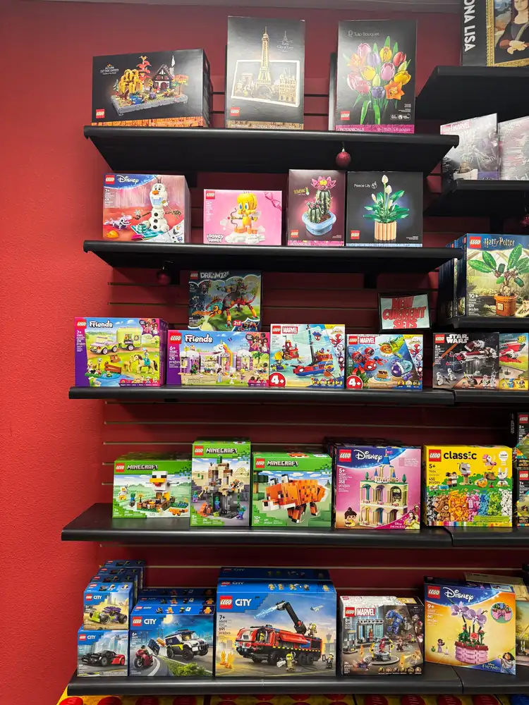 Boxed LEGO® sets on dark shelves against a red wall.