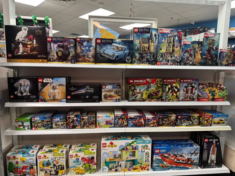 Boxed LEGO® sets arranged across a white freestanding shelving unit.