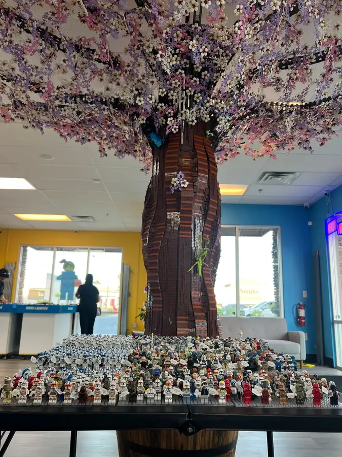 Rows of LEGO® Star Wars minifigures on a table beneath the Henderson store tree.