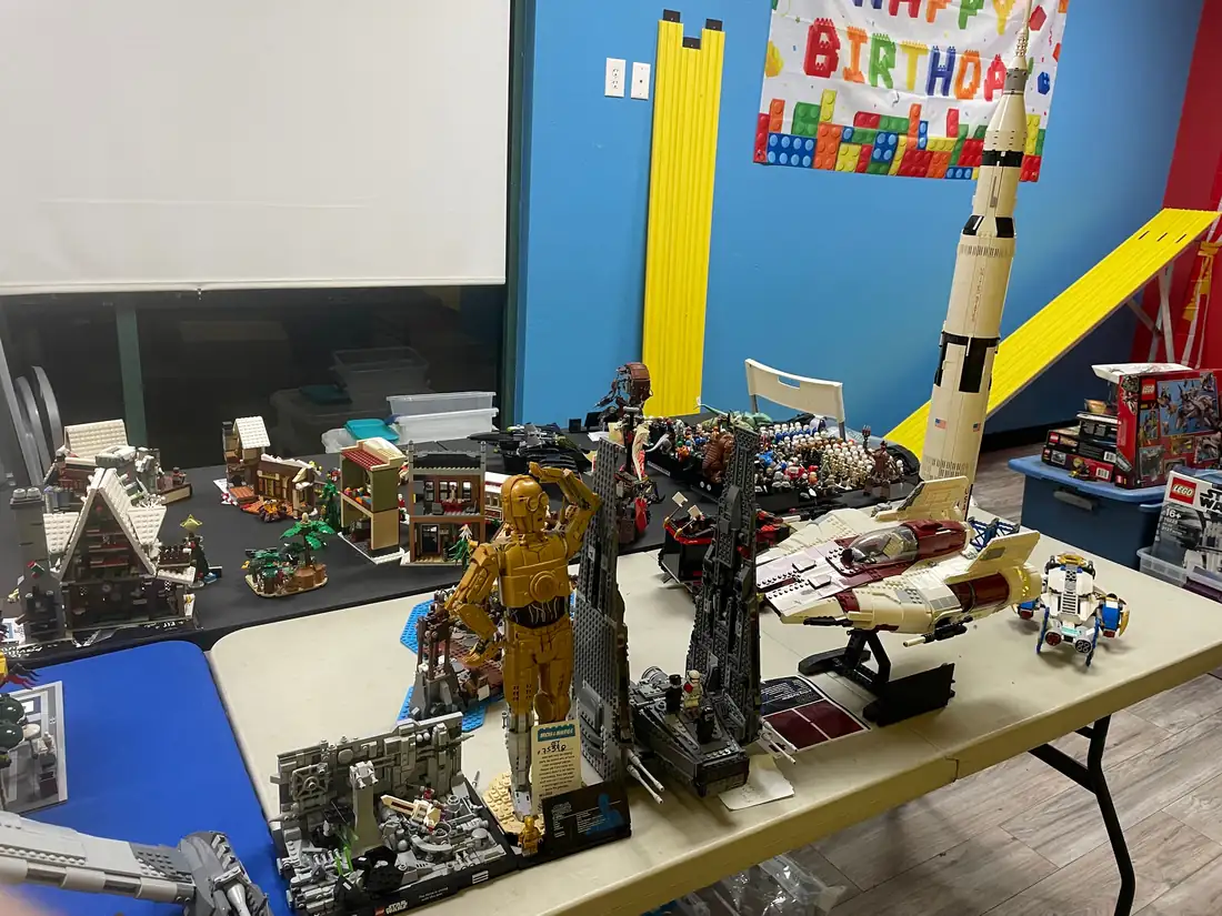 Assembled LEGO® models spread across tables, including a tall gray structure.