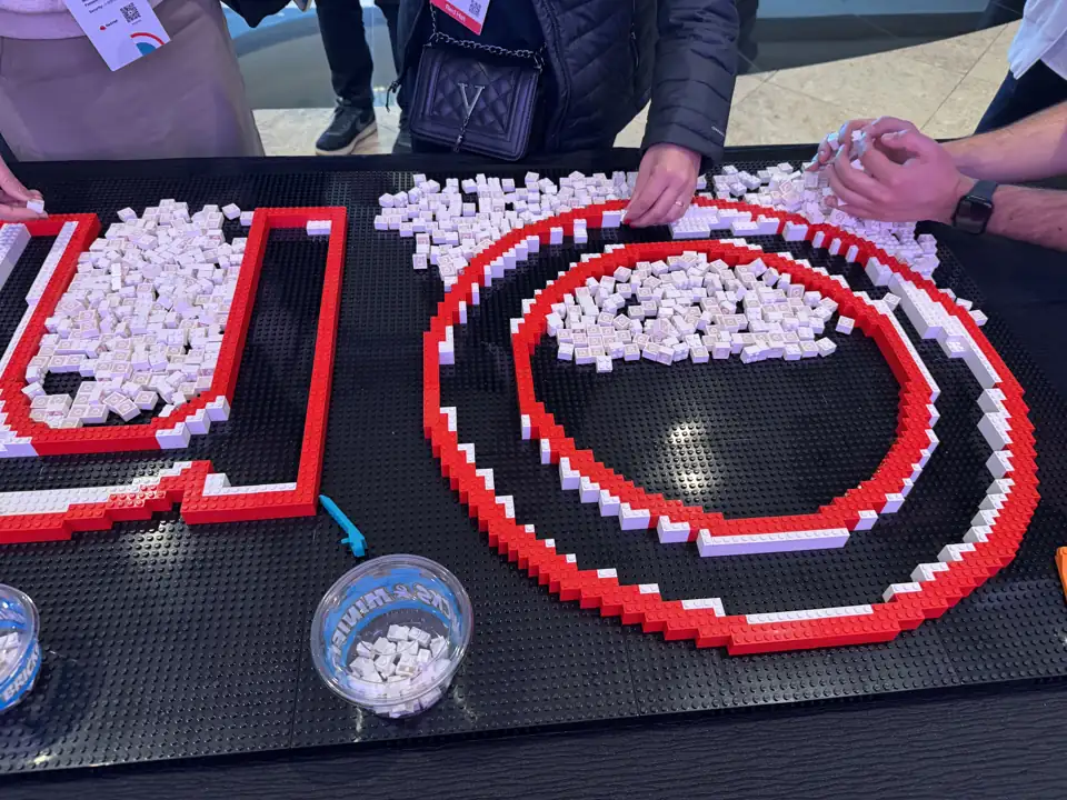 Event guests add pieces to a shared red-and-white brick mosaic.
