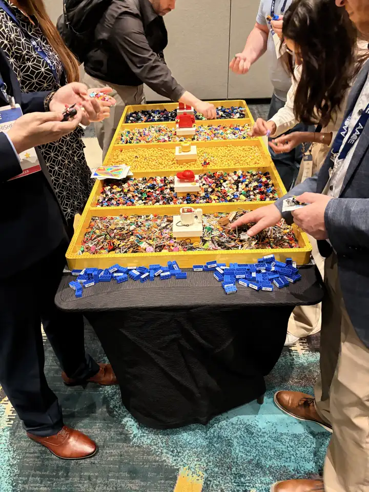 Guests choose parts from trays at a staffed minifigure-building station.
